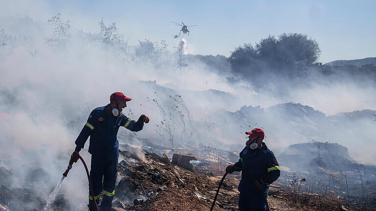 468731923.jpg       -  Feuerwehrleute versuchen, ein Feuer zu löschen, während ein Löschhubschrauber Wasser im Vorort Koropi im Osten von Athen abwirft.