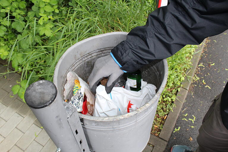 Der Flaschensammler achtet darauf, dass er Müll im Eimer bleibt, wenn er darin wühlt.