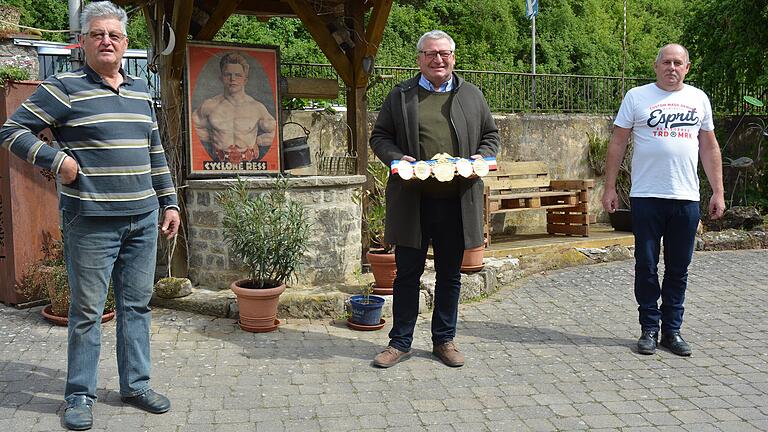 Schreiben die Geschichte von Weltmeister Cyclone Ress neu (von links): Arno Ress vor dem Plakat seines Großonkels, Bürgermeister Georg Menninger mit dem Weltmeistergürtel und Ringerexperte Joachim Baumeister. Schreiben die Geschichte von Weltmeister Cyclone Ress neu (von links): Arno Ress vor dem Plakat seines Großonkels, Bürgermeister Georg Menninger mit dem Weltmeistergürtel und Ringerexperte Joachim Baumeister.