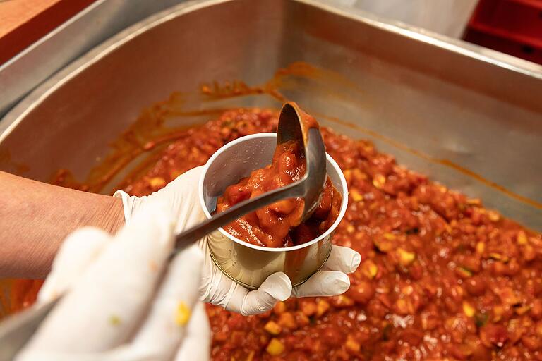 Nachdem alles gut durchgemischt ist, füllt eine Mitarbeiterin das fertige Ratatouille in die Dosen.