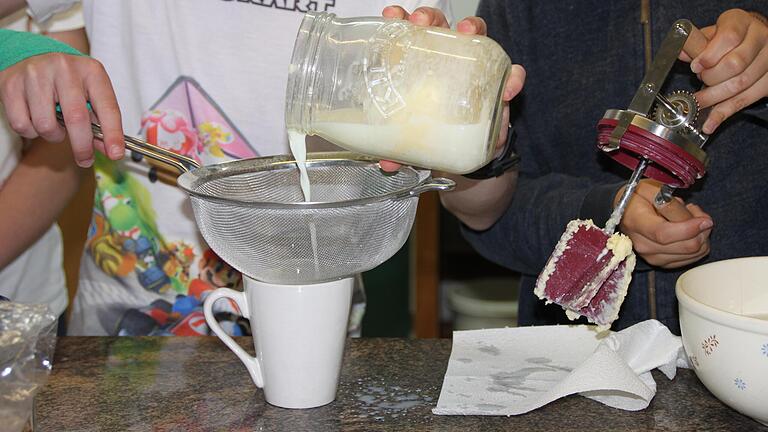 Die Buttermilch wird mithilfe eines Siebes von der fertigen Butter getrennt.       -  Die Buttermilch wird mithilfe eines Siebes von der fertigen Butter getrennt.