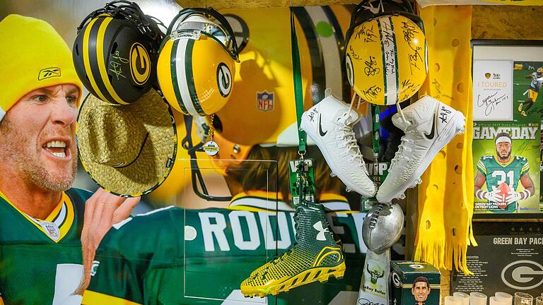 Signierte Helme und Schuhe von den Green Bay Packers. Im Hintergrund zu sehen: ein riesiges Bild der beiden Ex-Packers-Quarterbacks Brett Favre (links) und Aaron Rodgers.