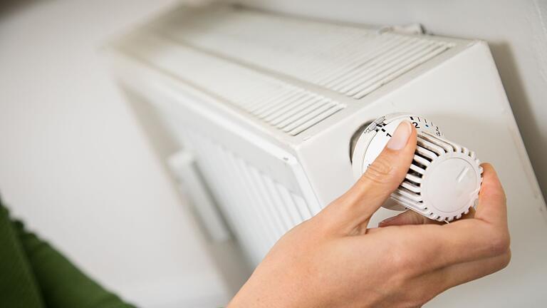 Eine Person dreht an einem Thermostat       -  Die Heizung schon im Frühjahr ausschalten? Laut Experten ist das keine gute Idee.