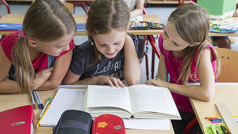 Three schoolgirls reading a book model released Symbolfoto property released PUBLICATIONxINxGERxSUIx       -  Gymnasium, Realschule, Mittelschule - nach der vierten Klasse steht der Wechsel in die weiterführende Schule an.