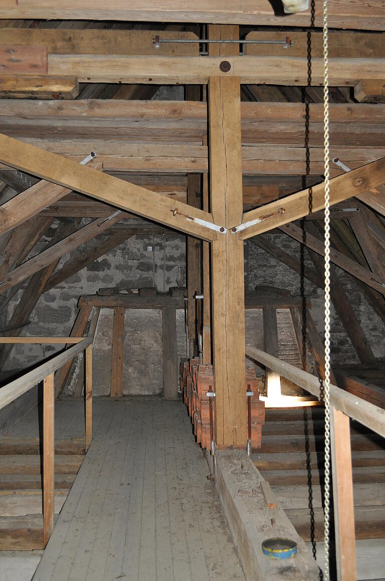 Auf dem Dachstuhl der evangelischen Kirche in Ermershausen ist im Hintergrund die Ummantelung des oberen Teils der Orgel zu sehen.