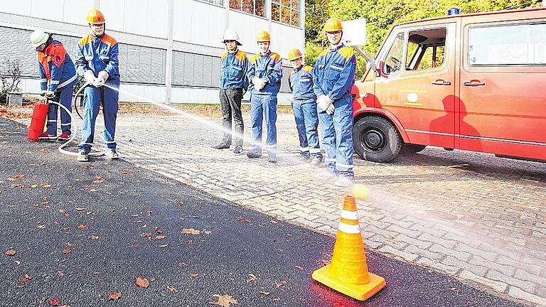 Mit der mobilen Handpumpe können kleine Brände bekämpft werden. Doch bevor sie echte Feuer löschen, müssen die Feuerwehrschüler den Umgang und das Zielen mit dem Löschgerät üben. Dafür schießen sie Tennisbälle von Pilonen.