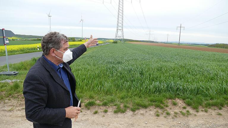 Arnsteins Bürgermeister Franz-Josef Sauer zeigt auf der 'Schraudenbacher Höhe' die gegenwärtige Stromversorgung mit Windrädern, Solaranlagen und großen Überlandleitungen auf. Im Hintergrund die Türme des ehemaligen Atomkraftwerks in Grafenrheinfeld.