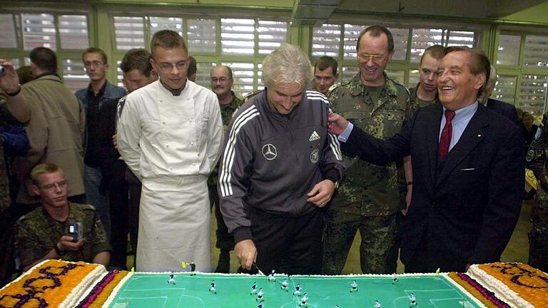 Nationalmannschaft besucht SFOR Lager - Rudi Völler (M) schneidet beim Truppenbesuch in Sarajevo eine Torte in Form eines Fußallplatzes an. Nationalmannschaft besucht SFOR Lager - Rudi Völler (M) schneidet beim Truppenbesuch in Sarajevo eine Torte in Form eines Fußallplatzes an.