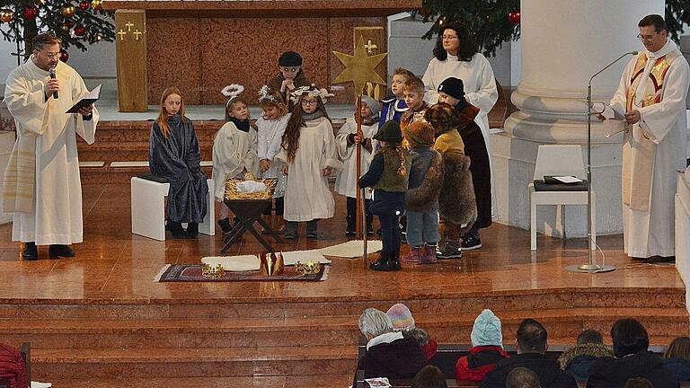 Begeisterte Kinder beim Krippenspiel in der Stadtpfarrkirche Mariä Himmelfahrt mit den 'Engeln' Diakon Thomas Prapolinat und Gottesdienstbeauftragter Sandra Kupfer sowie Dekan Andres Krefft.