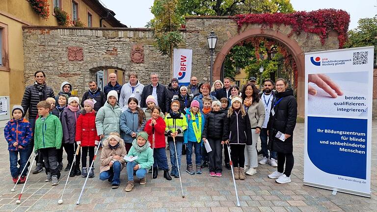 Gekommen waren am 'Tag des weißen Stocks' auf den Kirchplatz auch drei der vier dritten Klassen der Veitshöchheimer Grundschule, die verschiedene Hilfsmittel ausprobieren konnten, im Bild mit den BFW-Leuten die Klasse 3b mit Konrektorin Julia Heres (links).