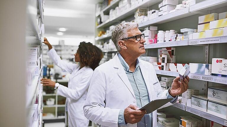 Stocking up. Shot of two focused pharmacist walking around and doing stock inside of a pharmacy.       -  In deutschen Apotheken bleiben mittlerweile viele Regale leer. Über 250 Medikamente - darunter Allerweltsmedikamente wie Fiebersäfte und Schmerzmittel - sind aktuell nicht lieferbar.