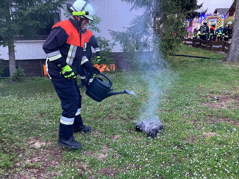 Mit der Gießkanne löschte dieser Feuerwehrmann die brennenden Holzscheite aus dem Kachelofen.