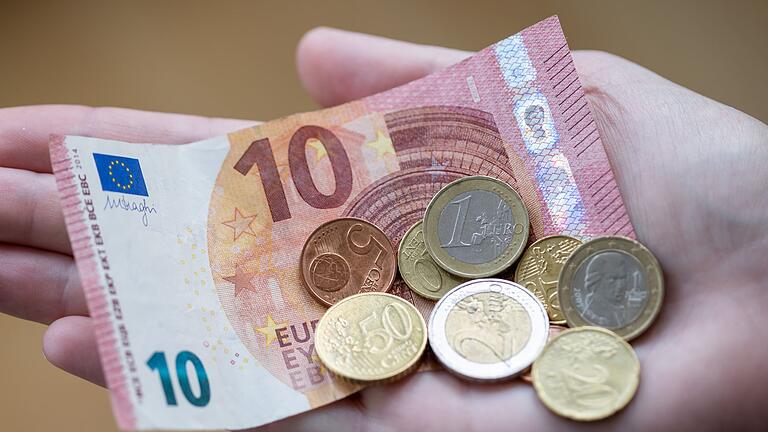 Geld       -  Eine Frau hält Geldscheine und Münzen in der Hand.