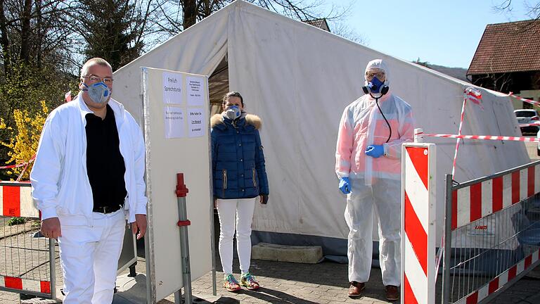 Mit Schutzanzug und Mundschutzmaske werden in der Hausarztpraxis Dres. Raab/Scheuerlein in Arnstein Corona-Patienten und Corona-Verdachtsfälle außerhalb der Praxisräume behandelt. Das Out-door-Zelt wurde von der BRK-Bereitschaft Arnstein zur Verfügung gestellt und aufgebaut. Auf dem 'kleinen Dienstweg' genehigte Bürgermeister Franz-Josef Sauer die Sperrung des Bettendorfplatzes und organisierte eine Gebläseheizung für das Freiluft-Zelt. Im Bild (von links) Praxisleiter Christian Raab, Medizinische Fachangestellte Sabine Veeh und Allgemeinmediziner Dr. Wulf Mattiesen. Mit Schutzanzug und Mundschutzmaske werden in der Hausarztpraxis Dres. Raab/Scheuerlein in Arnstein Corona-Patienten und Corona-Verdachtsfälle außerhalb der Praxisräume behandelt. Das Out-door-Zelt wurde von der BRK-Bereitschaft Arnstein zur Verfügung gestellt und aufgebaut. Auf dem 'kleinen Dienstweg' genehigte Bürgermeister Franz-Josef Sauer die Sperrung des Bettendorfplatzes und organisierte eine Gebläseheizung für das Freiluft-Zelt. Im Bild (von links) Praxisleiter Christian Raab, Medizinische Fachangestellte Sabine Veeh und Allgemeinmediziner Dr. Wulf Mattiesen.