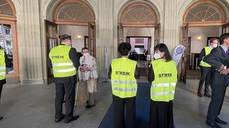 Orchester-Mitglieder in Streikwesten machten nach dem Festakt 'Wir sind Welterbe' im Foyer des Kissinger Regentenbaus auf ihre Situation aufmerksam.