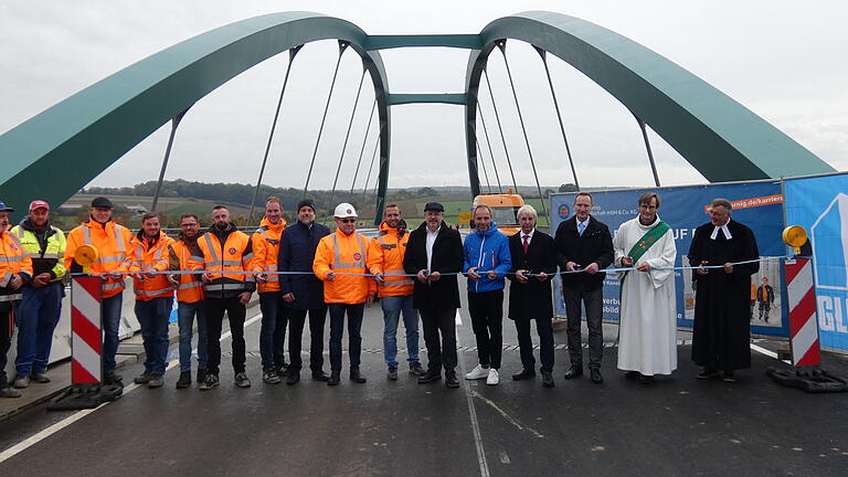 Mit dem Durchschneiden eines blau-weißen Bandes, wurde die Mainbrücke offiziell für den Verkehr freigegeben. Das Bild zeigt (von rechts): Pfarrer Thomas Prusseit, Diakon Michael Nowak, stellvertretender Landrat Michael Ziegler, Gebietsabteilungsleiter Manfred Rott (Staatliches Bauamt), Bürgermeister Michael Schneider, Behördenleiter Michael Fuchs und Vertreter der am Bau beteiligten Firmen. Mit dem Durchschneiden eines blau-weißen Bandes, wurde die Mainbrücke offiziell für den Verkehr freigegeben. Das Bild zeigt (von rechts): Pfarrer Thomas Prusseit, Diakon Michael Nowak, stellvertretender Landrat Michael Ziegler, Gebietsabteilungsleiter Manfred Rott (Staatliches Bauamt), Bürgermeister Michael Schneider, Behördenleiter Michael Fuchs und Vertreter der am Bau beteiligten Firmen.