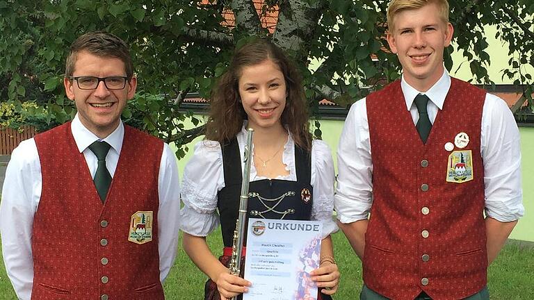 D3-Leistungsprüfung: Gold für Christina Hauck       -  (hb)  Ein Hauch von Olympia weht durch Michelau. Kürzlich absolvierte Christina Hauck die D3-Leistungsprüfung des Nordbayerischen Musikbundes an der Bayerischen Musikakademie in Hammelburg. Die junge Musikerin musste auf ihrer Flöte nicht nur sämtliche Tonleitern auswendig vortragen, sondern auch eine Auswahl von sechs Pflichtstücken und ein Selbstwahlstück der Prüfungsjury präsentieren. Neben schwierigen technischen Passagen, bei denen die Finger der Musikerin nur so über das Instrument flogen, waren sehr ausdrucksstarke, intensive Stellen zu meistern, die ein hohes Einfühlungsvermögen in die Musik erforderten. Darüber hinaus waren Gehörbildung und allgemeine Musiktheorie Prüfungsbestandteile. Christina Hauck bestand die Prüfung mit der Traumnote 1,3 und erhielt damit das goldene Leistungsabzeichen, die höchste Auszeichnung des Nordbayerischen Musikbundes für Jungmusiker. Die Heimatkapelle Michelau ist sehr stolz auf ihre Musikerin. Die beiden Vorsitzenden Marco Wolf (links) und Michael Ständecke gratulierten. Der weitere musikalische Werdegang führt Christina Hauck nun an die Berufsfachschule für Musik in Bad Königshofen, wo sie die Qualifikation für ein Studium an einer Musikhochschule erwerben möchte.