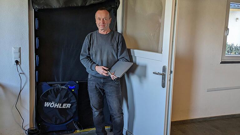 Mittels einer Plane dichtet Dieter Herrmann, Prüfer für Gebäude-Luftdichtheit, eine Hauseingangstür ab. Ein Ventilator erzeugt Unterdruck. Mittels einer Plane dichtet Dieter Herrmann, Prüfer für Gebäude-Luftdichtheit, eine Hauseingangstür ab. Ein Ventilator erzeugt Unterdruck. 