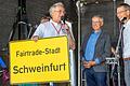 Die Lokale Agende 2030 in Schweinfurt feiert 25. Geburtstag  auf dem Georg-Wichtermann-Platz. Manfred Röder (Sprecher der Arbeitsgruppe Klimafreundliche Mobilität, links) übergab Oberbürgermeister Sebastian Remelé (rechts) ein neues Stadtschild.&nbsp; Da musste auch Fairtrade-Pionier Dieter Overath schmunzeln.
