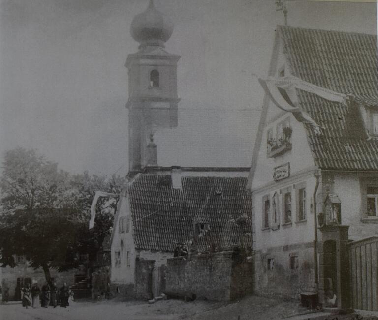 Eine alte Ortsansicht von Schraudenbach zeigt neben der Kirche die Dorflinde, die mittlerweile gefällt ist. Die beiden Häuser gibt es auch nicht mehr.