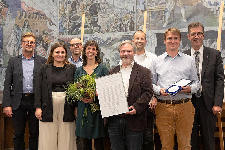 Verleihung der Medaille und Urkunde an den blauen Eumel (von links): Achim Könnecke (Kulturreferent der Stadt Würzburg, Julia Wolpold, Martin Schiessler, Katharina Lobé, Boris Wagner, Tobias Schirmer, Jan Kuhlmann sowie Christian Schuchardt (OB der Stadt Würzburg). Verleihung der Medaille und Urkunde an den blauen Eumel (von links): Achim Könnecke (Kulturreferent der Stadt Würzburg, Julia Wolpold, Martin Schiessler, Katharina Lobé, Boris Wagner, Tobias Schirmer, Jan Kuhlmann sowie Christian Schuchardt (OB der Stadt Würzburg).