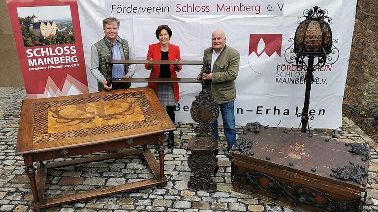 Michael Haupt aus Dittelbrunn (rechts) hat  dem Förderverein Schloss Mainberg einen Holztisch mit Hirschkopf-Intarsie,  eine elektrische schmiedeeiserne Stehlampe, eine Holzkiste mit Metallbeschlägen und Franken-Wappen sowie einen Holzstuhl im Renaissancestil und eine Garderobe geschenkt. Die beiden Vorsitzenden Christine Bender und Thomas Horling freuen sich über das Geschenk.