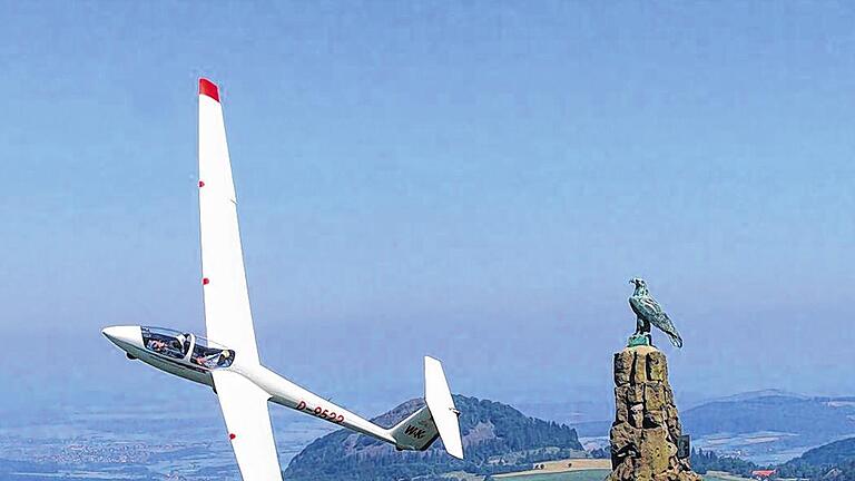 Wahrzeichen der Wasserkuppe: Weit ins Land blickt der bronzene Adler, an dem dieser Segelflieger vorbei gleitet.