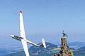 Wahrzeichen der Wasserkuppe: Weit ins Land blickt der bronzene Adler, an dem dieser Segelflieger vorbei gleitet.