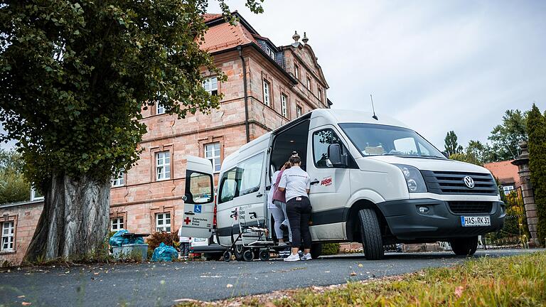 Kräfte des BRK Haßberge helfen den Bewohnerinnen und Bewohnern in die bereitstehenden Transporter, die sie zur neuen Unterkunft bringen sollen.