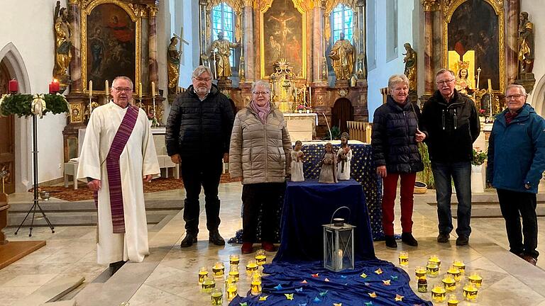 Um das Friedenslicht von Bethlehem und die Verkündigungsszene viele Lichter und Sterne sowie von links Diakon Lorenz Kleinschnitz und die Mitwirkenden Manfred Thomann, Brigitte Schlicker, Rosalinde Czeschka, Günther Schösser und Ludwig Walter.  Auf dem Bild fehlt Gabriele Mergenthaler.