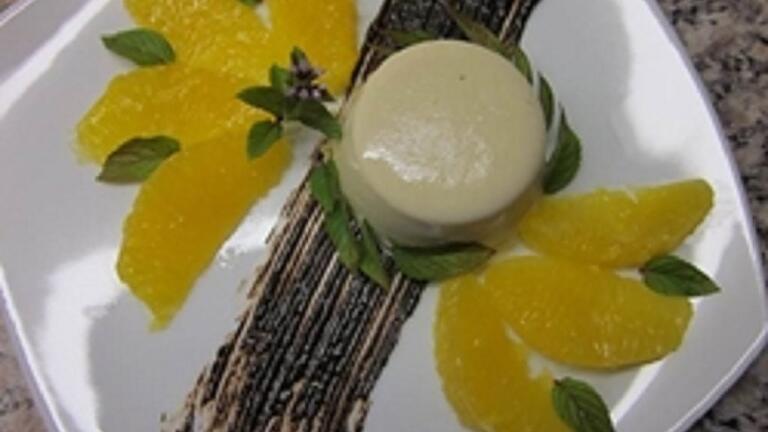 Die Kaffee-Pannacotta wird mit Orangenfilets auf einem Schokoladenspiegel serviert.