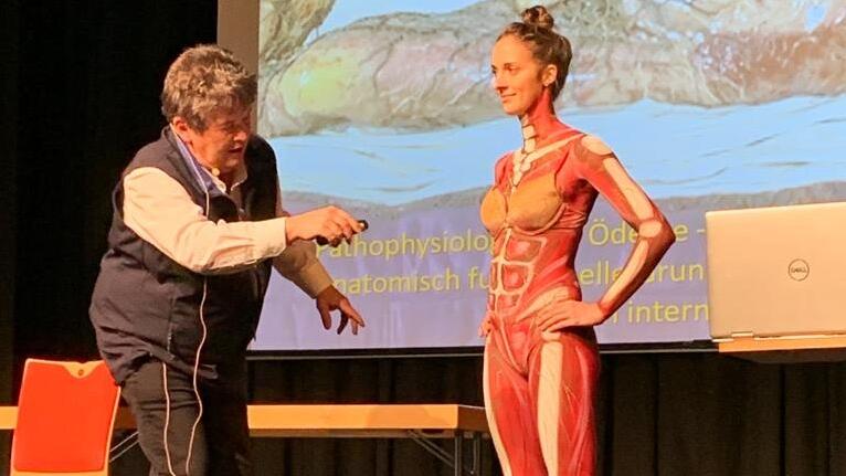 Oliver Gültig (Geschäftsführer Lymphologic GmbH) und Marion de Tomaso (Bodypainting-Model mit Lymphgefäßsystem) während eines Vortrags zur schematischen Erklärung des Lymphgefäßsystems anhand des Models.