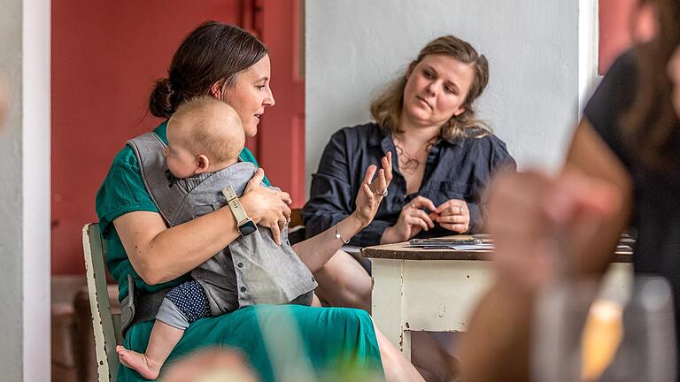 Josefine Wallach (rechts) und die Inhaberin des 'Wunschlos glücklich', Hannah Seitz, mit ihrem Sohn auf dem Schoß im Café.