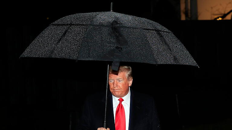 US-Präsident Trump.jpeg       -  Ex-Präsident Donald Trump schütz sich mit einem Regenschirm vor einem Schauer. In Deutschland wird debattiert, was nötig ist, wenn der nukleare Schutzschirm der USA nicht mehr da ist.