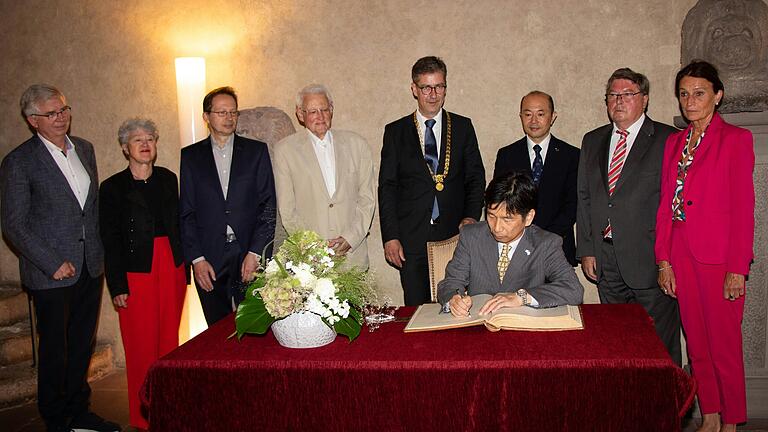 Der japanische Generalkonsul Kenichi Bessho (sitzend) trägt sich nach Oberbürgermeister Shiro Suzuki (Dritter von rechts) ins Goldene Buch der Stadt Würzburg ein (von links): die Stadtratsmitglieder MdB Prof. Dr. Andrew Ullmann, Christa Grötsch, Manfred Dürr, Willi Dürrnagel, Oberbürgermeister Christian Schuchardt, Altbürgermeister Dr. Adolf Bauer und Stadträtin Barbara Meyer.