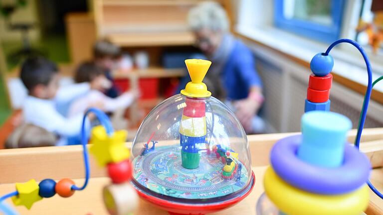 Kinderbetreuungsplätze sind in Gerolzhofen Mangelware. Über 50 Kinder warten auf einen Platz in einer Krippe oder im Regelkindergarten. Das Symbolbild zeigt hinter dem Spielzeug Kinder in einer Kita zusammen mit einer Erzieherin.