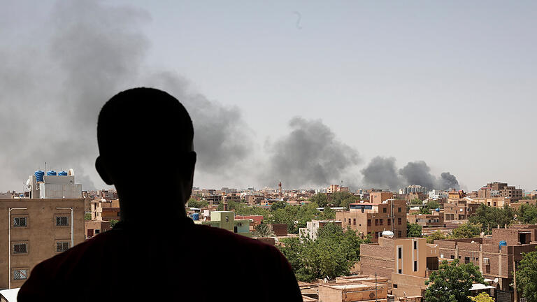 UN: Mehr als eine Million Binnenvertriebene im Sudan.jpeg       -  Ein Mann blickt auf die Stadt Khartum, wo schwarzer Rauch aufsteigt. Im Zuge der anhaltenden Kämpfe im Sudan ist die Zahl der Flüchtlinge massiv angestiegen.