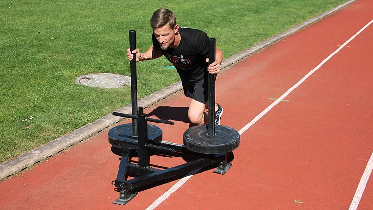 Hyrox-Weltmeister Lukas Storath schiebt einen 175 Kilo schweren Schlitten über die Tartanbahn der Würzburger Bereitschaftspolizei.