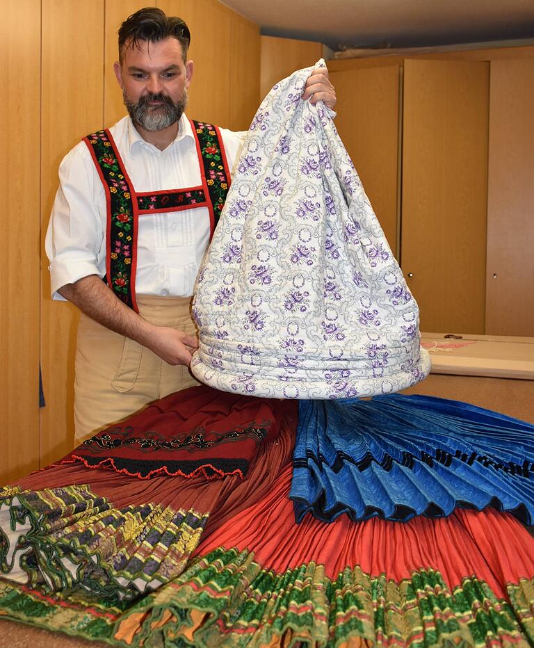 Nach 150 Jahren noch brillante Farben. Oliver Brust präsentiert einige Prachtstücke der Rock-Sammlung. Der Reifrock, den er in der Hand hält, sorgte darunter für die runde Trageform.