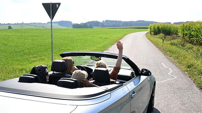 Im Cabrio unterwegs       -  Auto fährt auf einer Straße im Chiemgau.