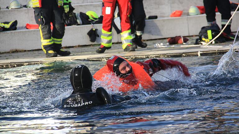 Nachdem der Träger des Überlebensanzugs ins Wasser gegangen ist, versucht er, den hilflosen Menschen möglichst schnell schwimmend zu erreichen.