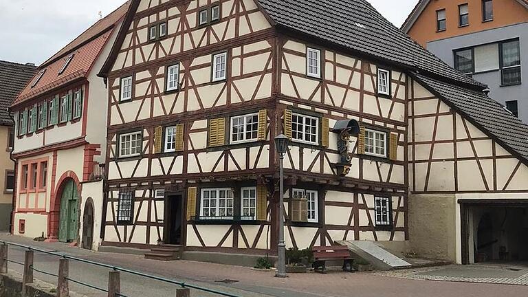 Die hölzerne Hausmadonna am Kirchplatz von Königheim, an der Fachwerkhauswand eines ehemaligen Kolonialwarenladens schräg gegenüber des Rathauses.