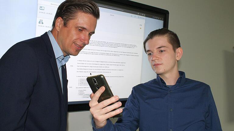 Total digital: Die IT-Firma FIS in Grafenrheinfeld (Lkr. Schweinfurt) hat ein Berichtsheft entwickelt, das mit Spracherkennung läuft: Nachdem Lehrling Mike Bieber (rechts) seine Einträge via App in sein Smartphone gesprochen hat, kann Ausbildungsleiter Stefan Seufert das Berichtsheft am Computer aufrufen und an die Leinwand (hinten) projizieren. Total digital: Die IT-Firma FIS in Grafenrheinfeld (Lkr. Schweinfurt) hat ein Berichtsheft entwickelt, das mit Spracherkennung läuft: Nachdem Lehrling Mike Bieber (rechts) seine Einträge via App in sein Smartphone gesprochen hat, kann Ausbildungsleiter Stefan Seufert das Berichtsheft am Computer aufrufen und an die Leinwand (hinten) projizieren.