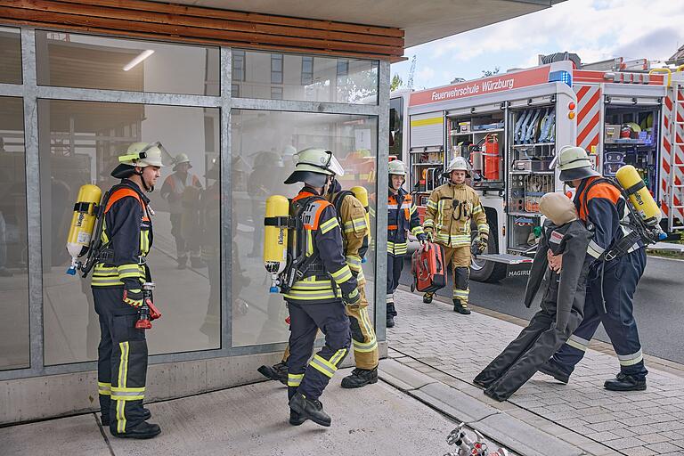 Feuerwehrleute ziehen einen 'Bewusstlosen' aus einer brennenden und verrauchten Tankstelle.