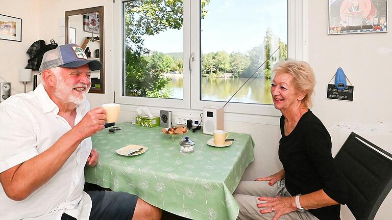 Fritz und Karin Drenker trinken gerne Kaffee an ihrem Tisch mit Seeblick - entweder im Anbau des Wohnwagens (im Bild) oder davor.