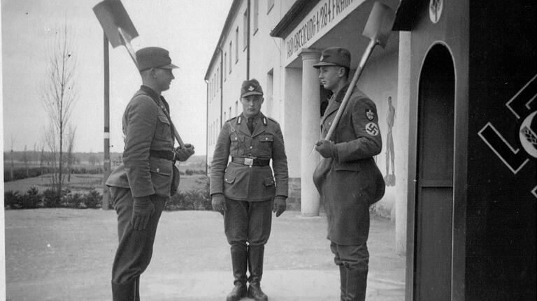 Wachablösung an der Torzufahrt des Gerolzhöfer RAD-Lagers: Der Spaten war für die Männer eine Art Ersatzgewehr. Während bei der Wehrmacht diverse Gewehr-Griffe zum Drill gehörten, gab es beim RAD die „Spatengriffe“.