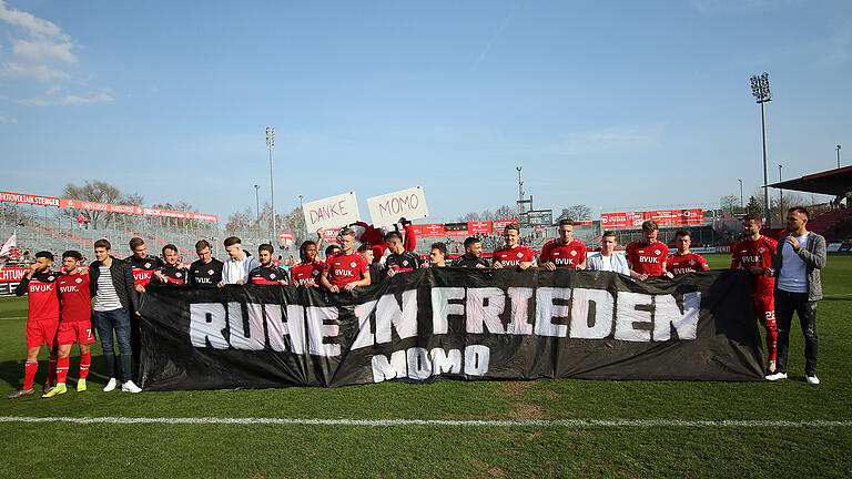 Die Kickers-Akteure halten nach der Partie gegen Münster das Transparent zum an den am Freitag verstorbenen Rothosen-Anhänger.
