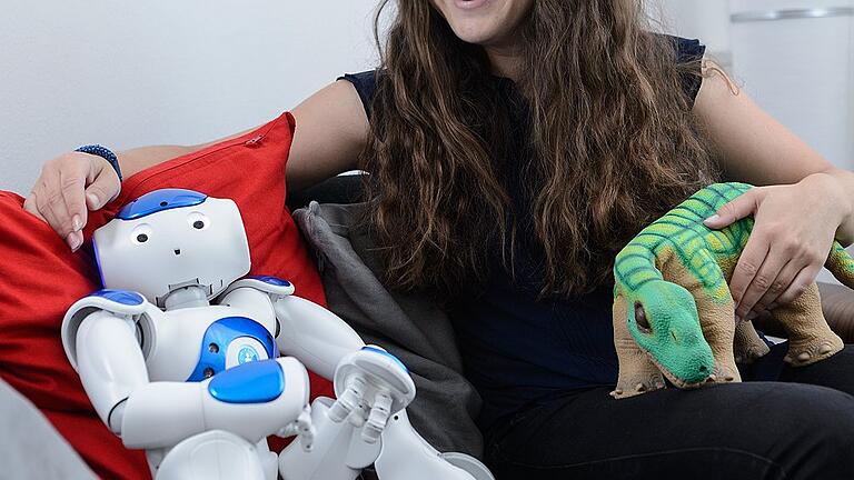 Echte Gefühle für künstliche Wesen? - Psychologin Isabelle Menne auf der Couch mit Nao und Pleo: Am Institut Mensch-Computer-Medien der Universität Würzburg erforscht sie, wie Menschen auf menschliche und tierische Roboter reagieren. Echte Gefühle für künstliche Wesen? - Psychologin Isabelle Menne auf der Couch mit Nao und Pleo: Am Institut Mensch-Computer-Medien der Universität Würzburg erforscht sie, wie Menschen auf menschliche und tierische Roboter reagieren.