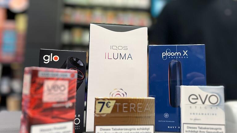 Tabakerhitzer verschiedener Marken       -  Die Tabakerhitzer-Elektrogeräte der Marken Glo von British American Tobacco (BAT), Iqos von Philip Morris und Ploom von Japan Tobacco International (JTI) mit den dazugehörigen Tabakstick-Marken liegen auf der Verkaufstheke eines Geschäfts.