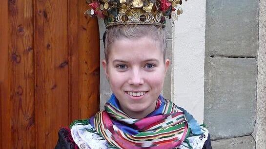 Sina Korbacher aus Geldersheim in der historischen Hochzeitstracht aus der Zeit um 1850. Eine alte Hochzeitstracht mit Flitterkranz und Seidentuch mit dem charakteristischen Muster. Dieses nennt man „geflammt“. Auffällig bei den damaligen Tüchern ist, dass sie nur mit kurzen Fransen oder Spitzen versehen sind. Bei der späteren Tracht waren durchaus 15 Zentimeter lange „Droudl“ (=Fransen) üblich.